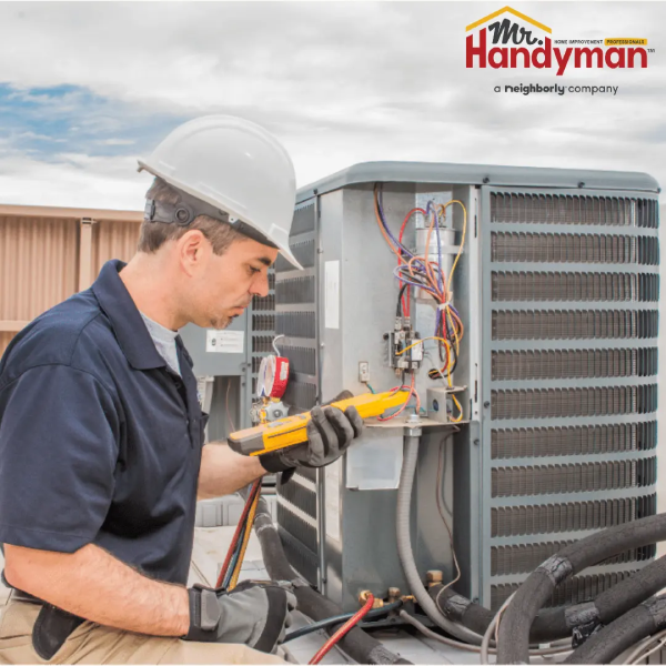 Mr. Handyman technician performing electrical work on an outdoor air conditioning unit.