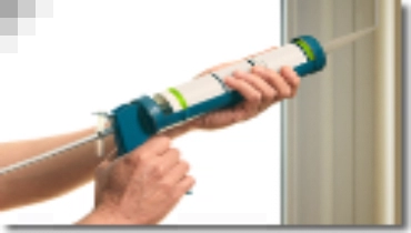 Applying caulk to a window frame.