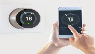 Smart Thermostat with a person using their phone to adjust room temperature.