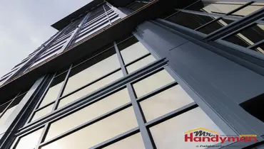 Handyman sealing a storefront window perimeter at a Cedar Hill, TX commercial property