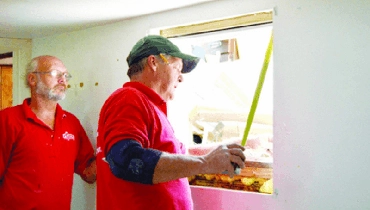 Handyman measuring wood plank Mr. Handyman repairmen measuring window